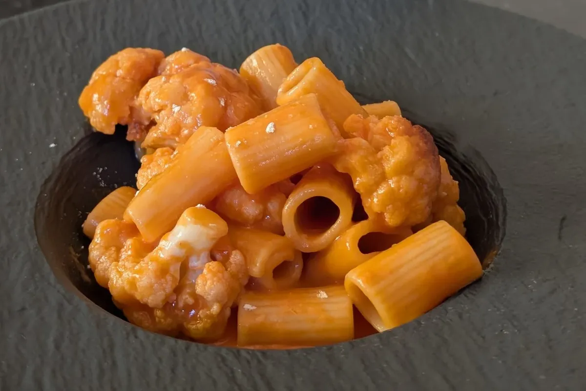 The real dish on the night: short tubes of pasta and browned cauliflower in an orange tomato and mascarpone sauce, served in a dark stone bowl