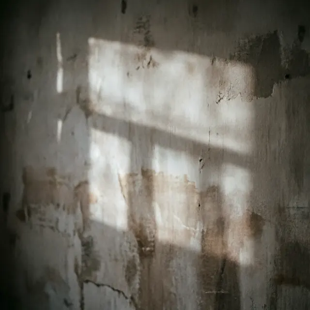A bare concrete wall with a soft rectangle of late afternoon light falling across it